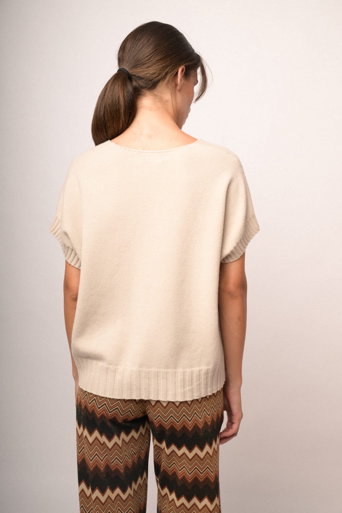 Chaleco de punto beige con espalda lisa y bajo acanalado.