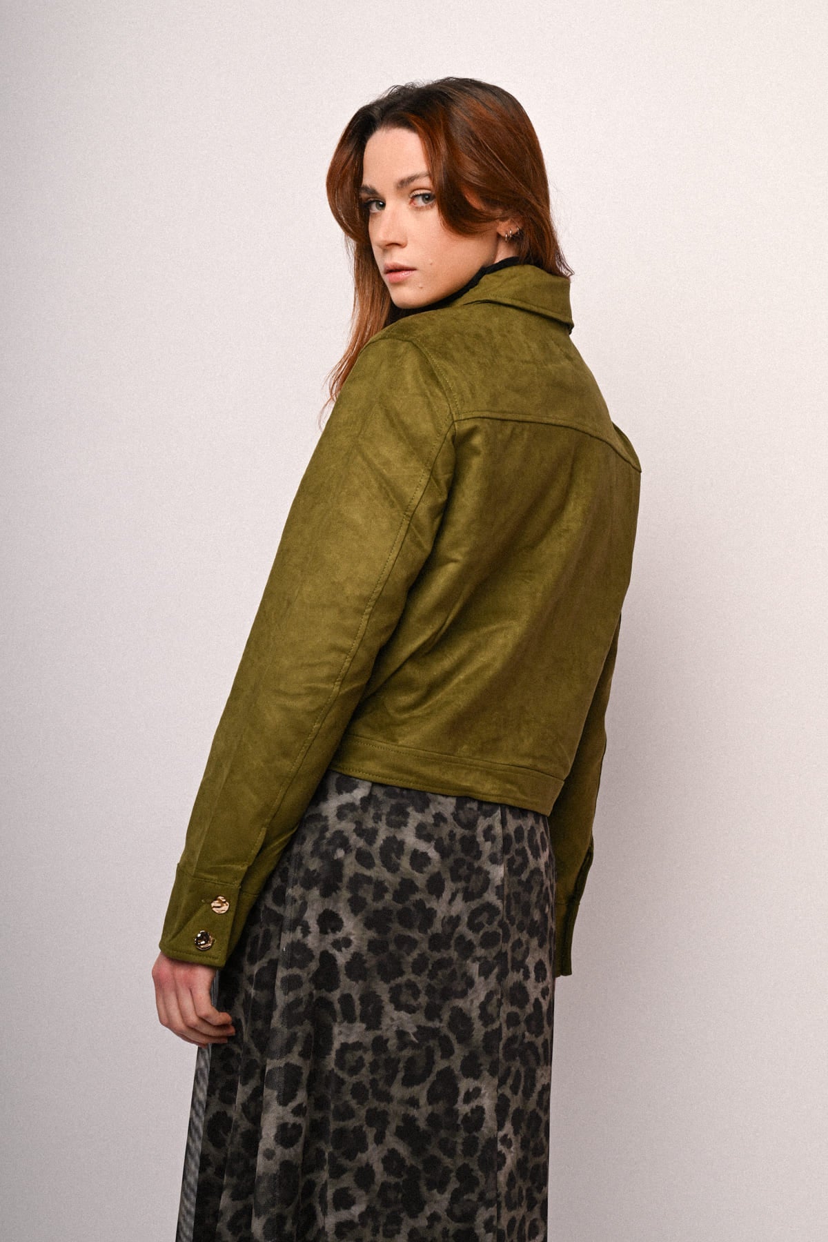 Chaqueta verde oliva de ante sintético con botones en puños y costuras visibles.