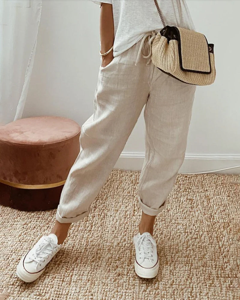 Pantalón fluido beige con cintura fruncida y puños elásticos, bolsillos laterales.
