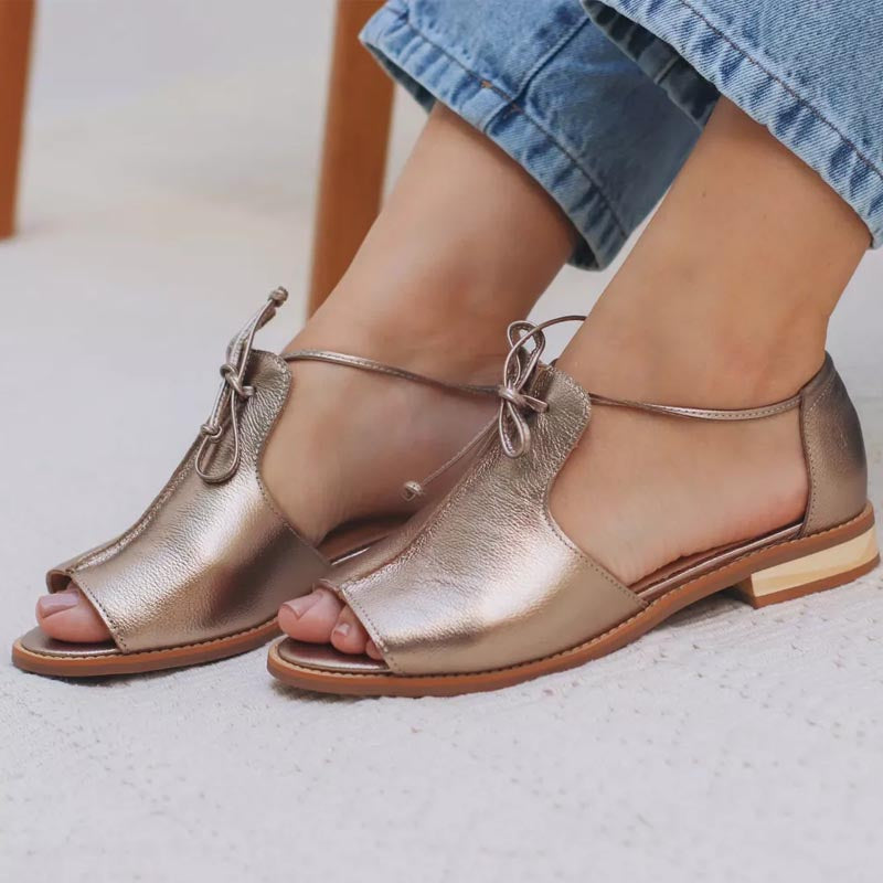 Sandalias metalizadas color champagne con lazo frontal y suela marrón