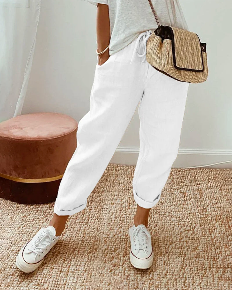 Pantalón fluido blanco con cintura fruncida y puños elásticos, bolsillos laterales.