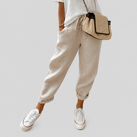 Pantalón fluido beige de lino, tiro elástico y bolsillos laterales, dobladillo ajustado.