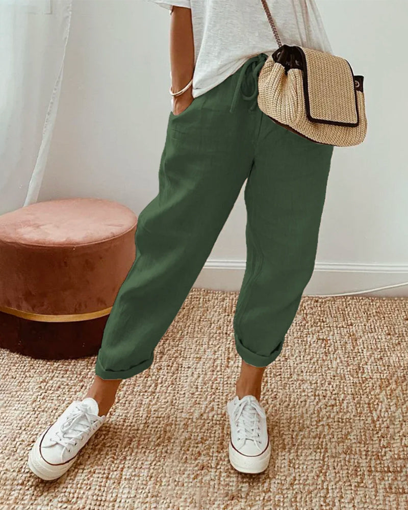 Pantalón fluido verde oscuro con cintura fruncida y puños elásticos, bolsillos laterales.