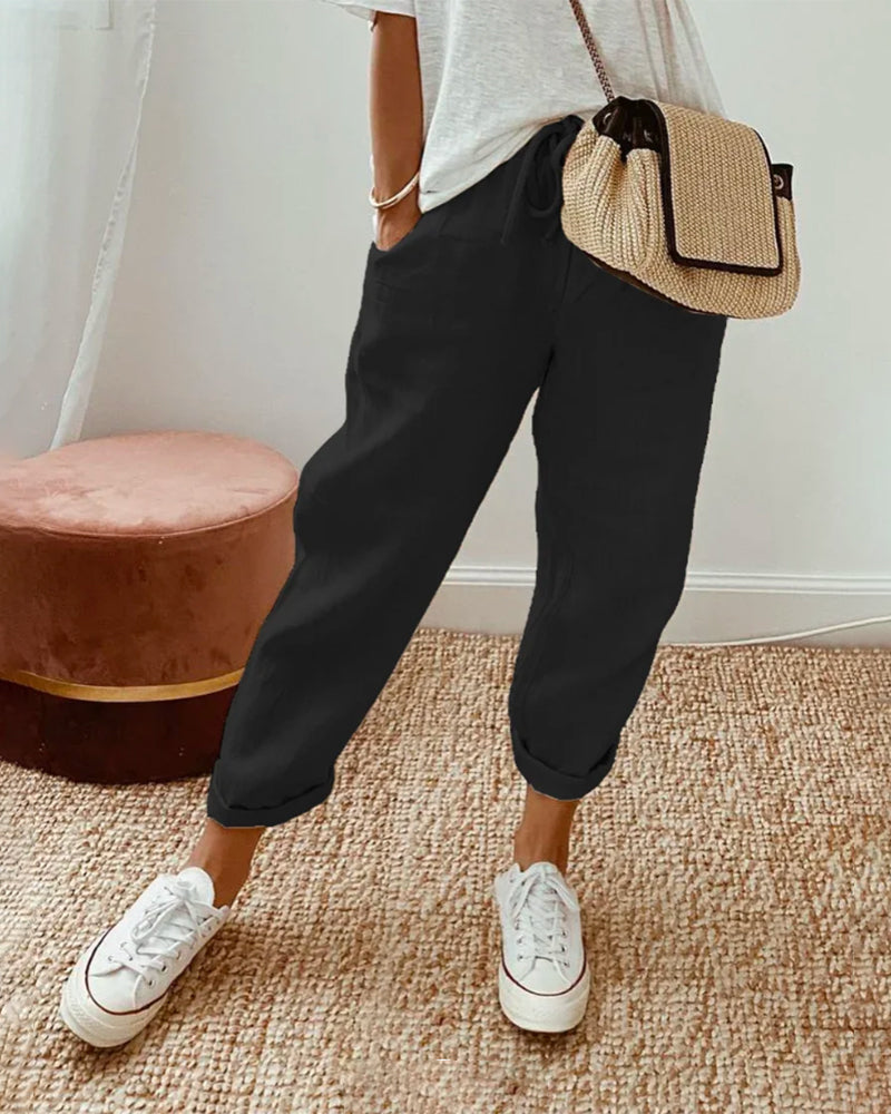 Pantalón fluido negro con cintura fruncida, puños elásticos y bolsillos laterales.