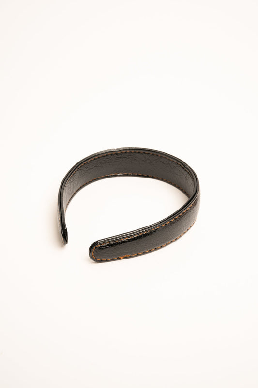 Diadema de polipiel negra con costuras naranjas y borde cosido.
