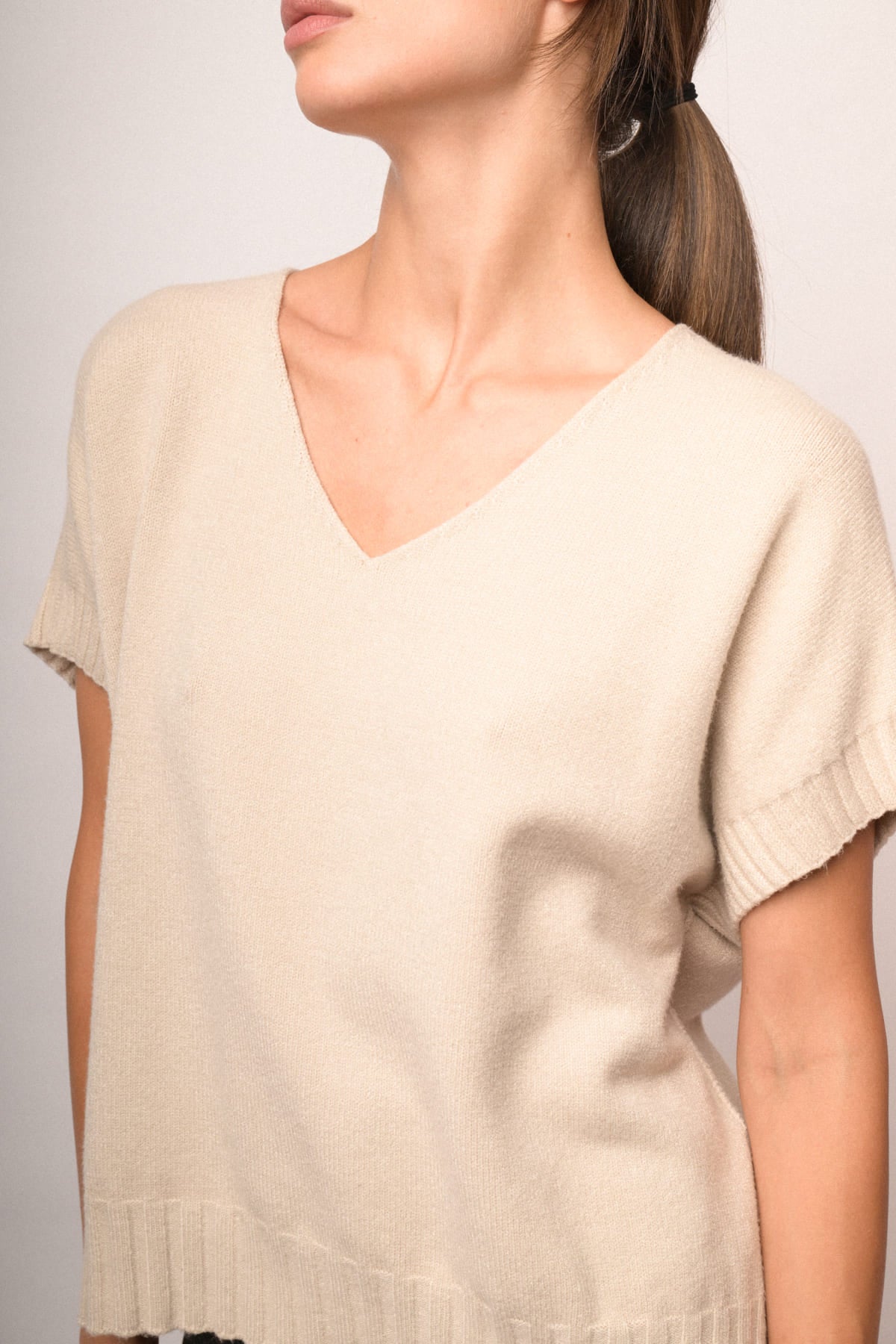 Chaleco de punto beige con escote en V y tejido fino liso; bajo acanalado.