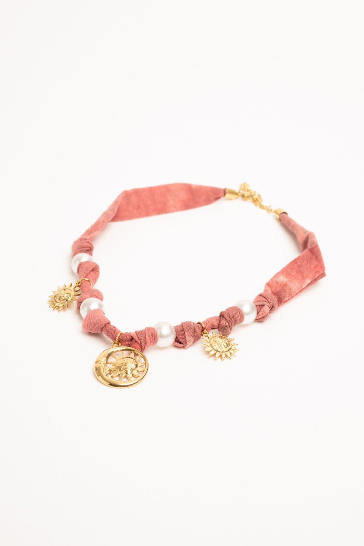Collar con tejido rosa, cuentas y colgantes dorados: medallón y motivos de sol