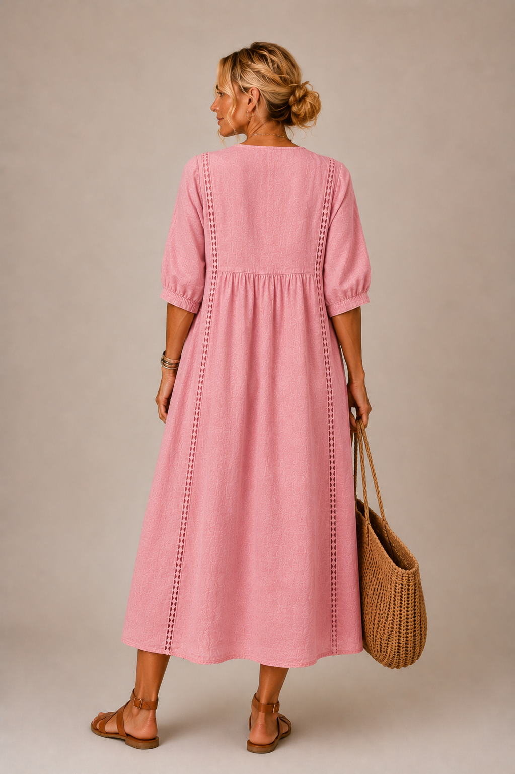 Vestido midi rosa visto de espalda, con botones y costura vertical, mangas abullonadas.
