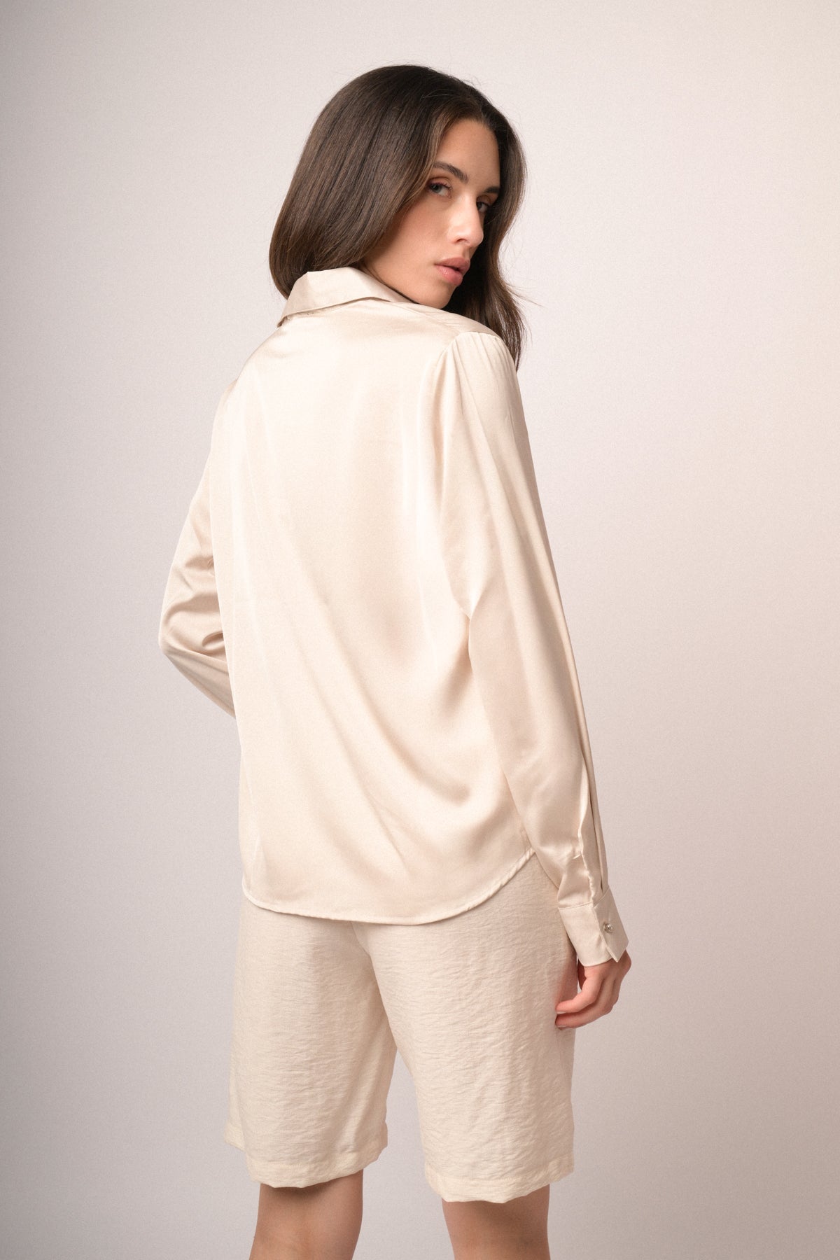 Camisa satinada beige con vista trasera lisa y puño con botón