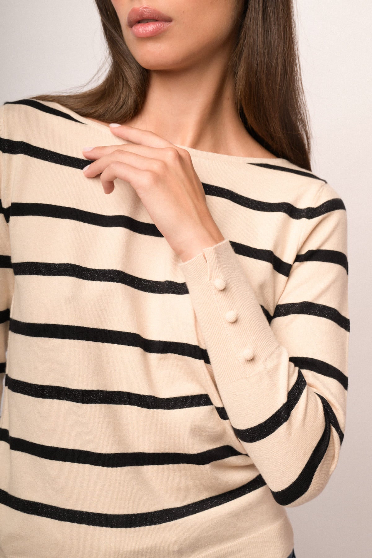 Jersey beige con rayas negras horizontales, cuello redondo y puños acanalados