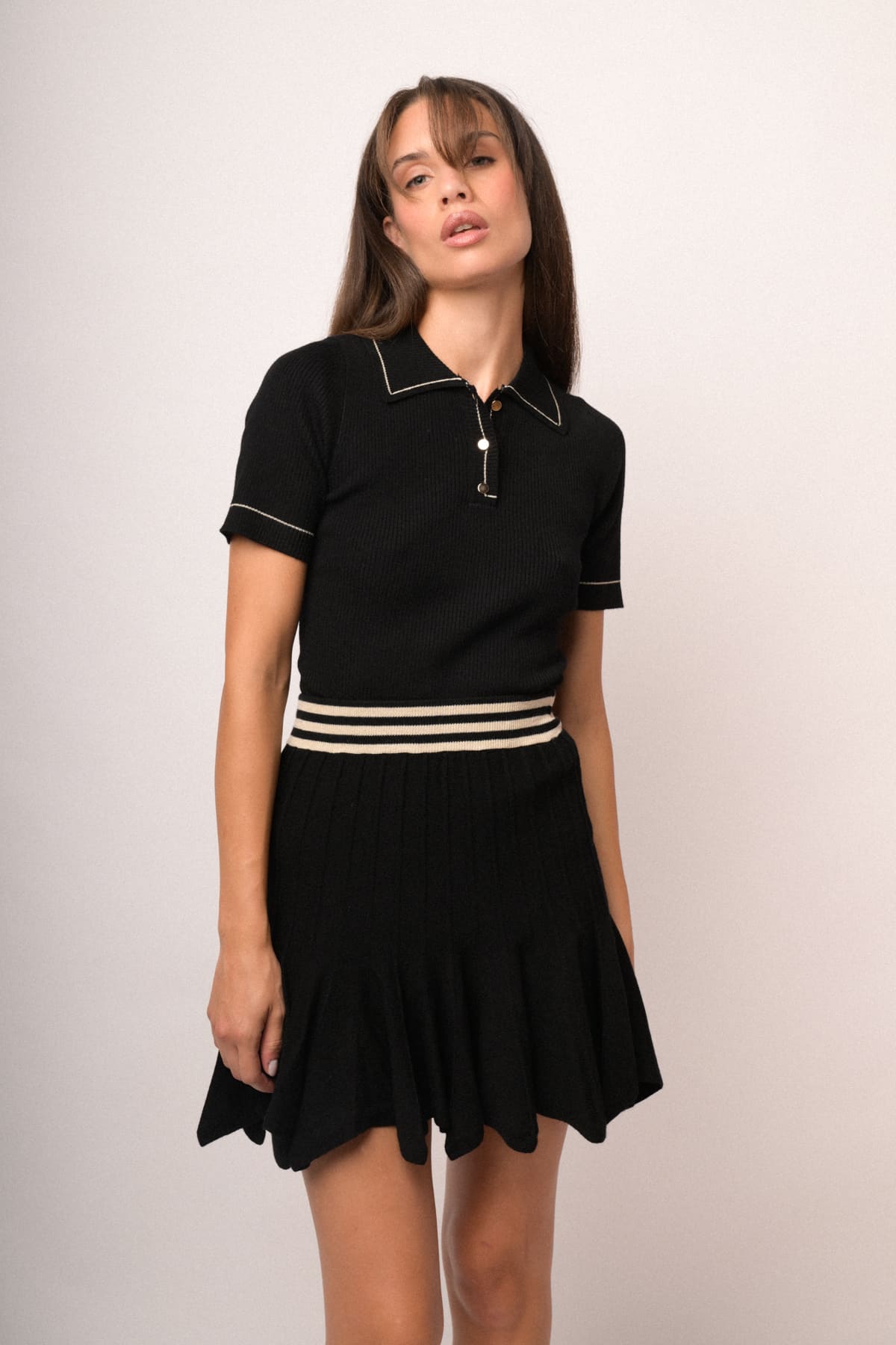 Vestido tipo jersey negro con ribetes beige, cremallera y falda plisada