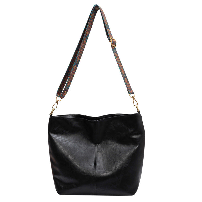 Bolso bandolera vintage negro con correa estampada y herrajes metálicos